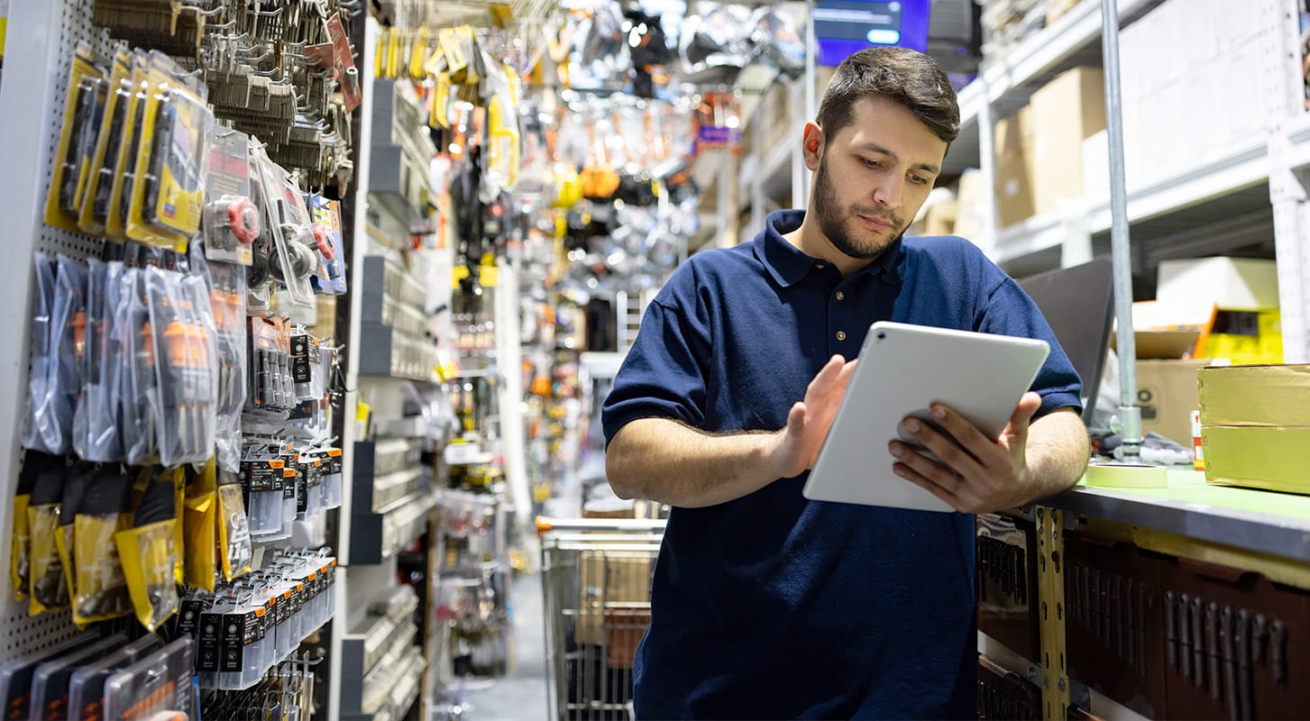 A man with a tablet in a store, analyzing supply chain information to enhance inventory control and optimize sales strategies.